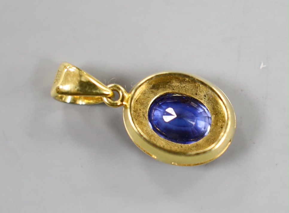 A modern 18k and oval cut sapphire set pendant, overall 22mm, gross weight 3.1 grams.